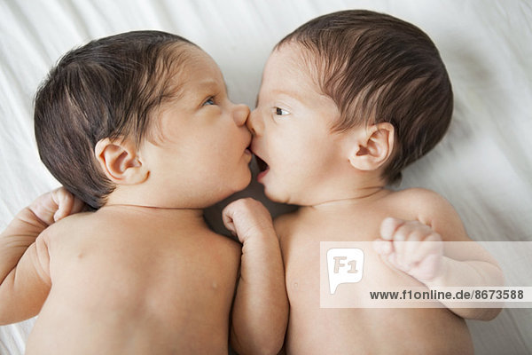 Twin baby girls kissing on bed