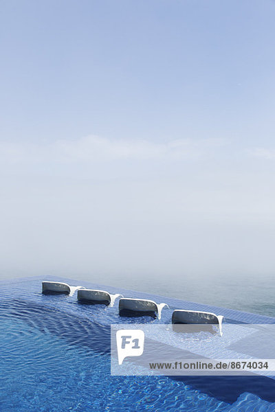 Liegestühle im Infinity-Pool mit Blick auf den Ozean