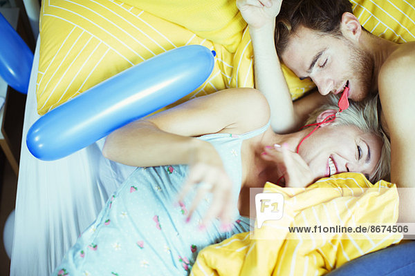 Couple playing in bed with balloons