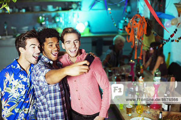 Men taking self-portraits with camera phone at party