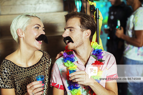 Couple wearing fake mustaches at party