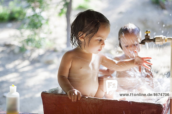 Baby-Mädchen spielen im Wasserspeier im Freien