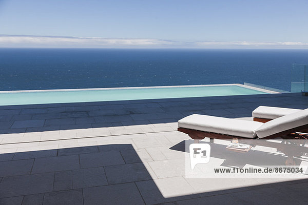 Liegestühle und Infinity-Pool mit Blick auf das Meer