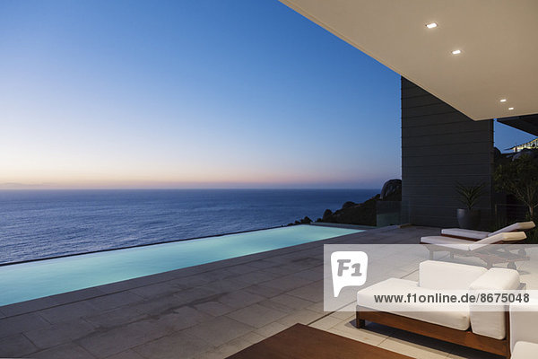 Moderne Terrasse und Infinity-Pool mit Blick auf das Meer bei Sonnenuntergang