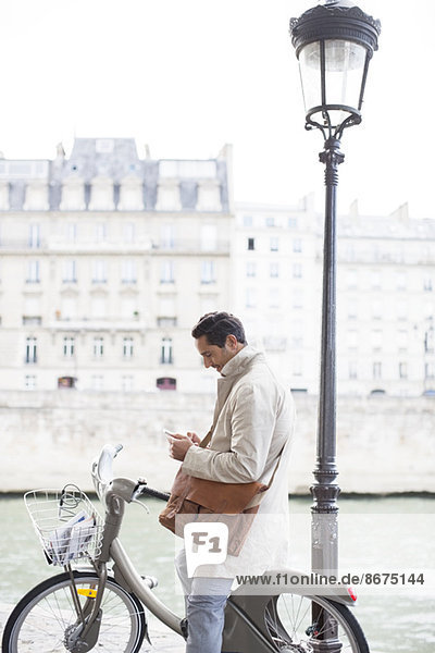Geschäftsmann mit Handy auf dem Fahrrad entlang der Seine  Paris  Frankreich