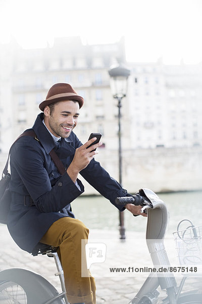 Geschäftsmann mit Handy auf dem Fahrrad entlang der Seine  Paris  Frankreich