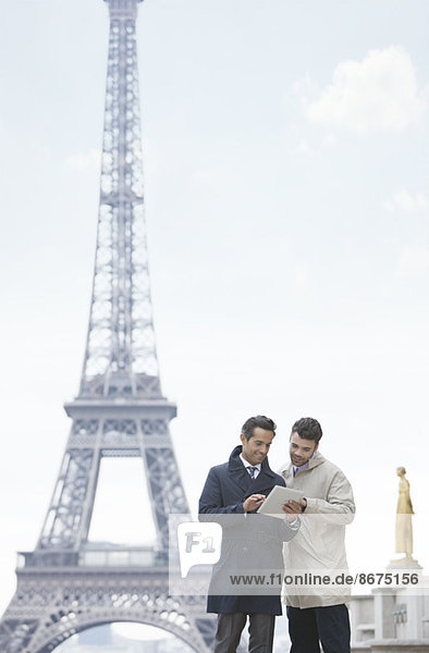 Businessmen using digital tablet by Eiffel Tower  Paris  France
