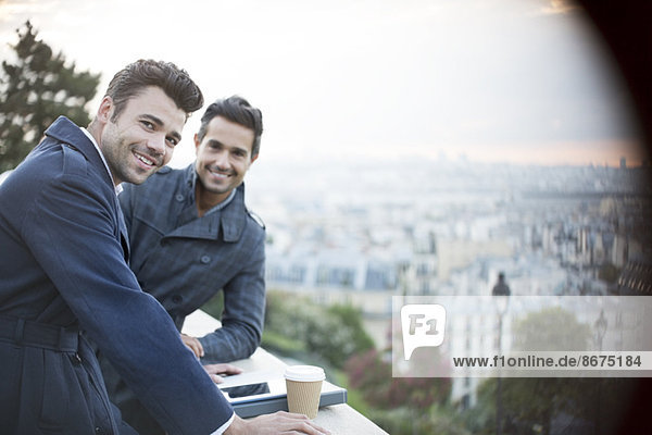 Businessmen smiling at railing overlooking Paris  France
