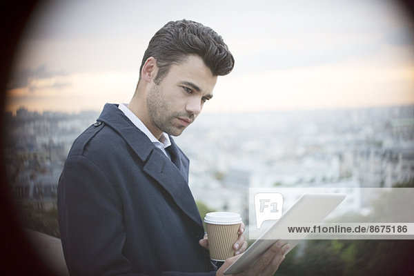 Geschäftsmann mit digitalem Tablett mit Blick auf Paris,  Frankreich