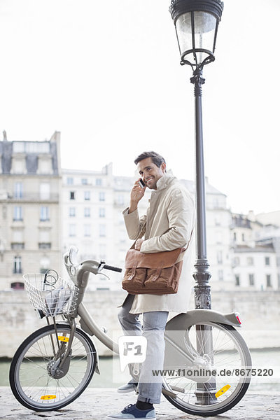 Businessman talking on cell phone on bicycle along Seine River  Paris  France