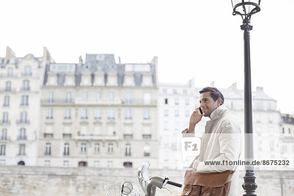 Geschäftsmann auf dem Fahrrad im Gespräch mit dem Handy in Paris  Frankreich