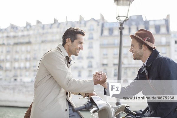 Businessmen shaking hands on bicycles along Seine River  Paris  France