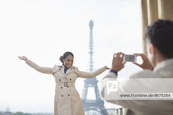 Mann fotografiert Freundin vor dem Eiffelturm  Paris  Frankreich
