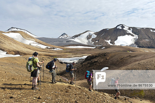 Trekking in the highlands  hiking group travelling downhill in single file  mountain landscape  glaciers and snowfields  Laugavegur hiking trail  Kaldaklofsfjöll  Rangárþing ytra  Suðurland  Iceland  Scandinavia