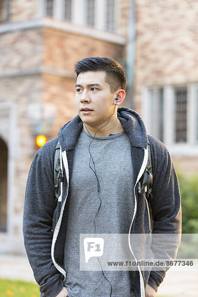 Mixed race college student listening to music on headphones