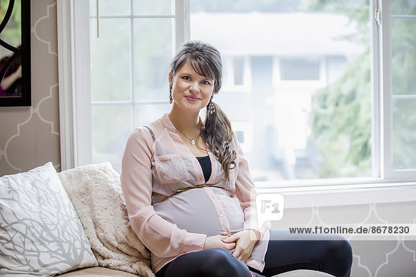 Pregnant Caucasian woman sitting on sofa