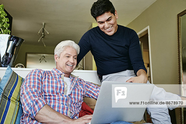 Homosexual couple using laptop in living room