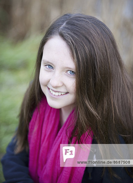 Ein junges Mädchen mit langen braunen Haaren und einem fuchsia-rosa Schal.
