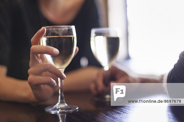 Zwei Personen  ein Paar sitzt in einer Bar und trinkt ein Glas gekühlten Weißwein.