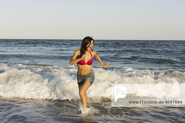 A beautiful young women at the water's edge on the beach in Atlantic City.