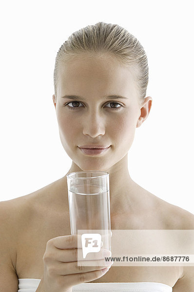 Ein Spa-Behandlungszentrum. Eine junge Frau trinkt ein Glas Wasser zur Hydratation.