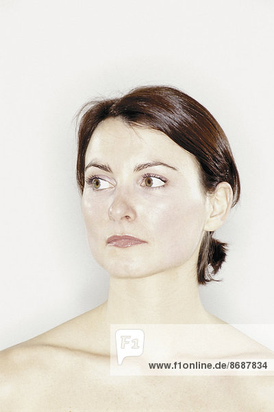 Ein Studioporträt einer Frau mit braunem Haar  das nach hinten aus dem Gesicht gebunden ist.