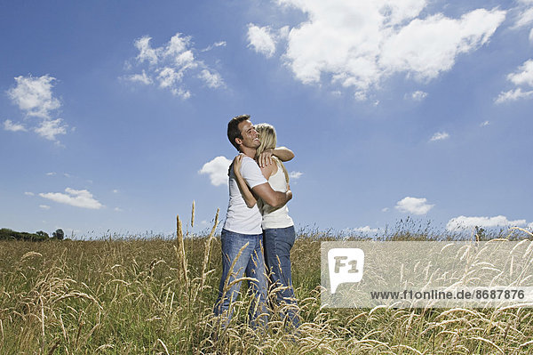 Ein Paar steht auf einem Weizenfeld und umarmt sich.