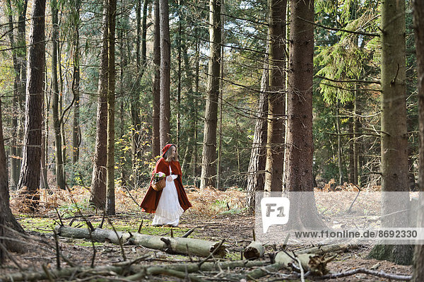 Mädchenmaskerade als Rotkäppchen im Wald unterwegs