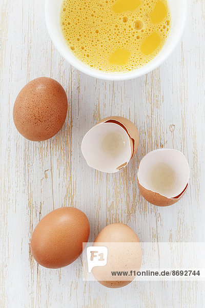 Schale mit aufgebrochenen Eiern und Eierschalen auf Holztisch