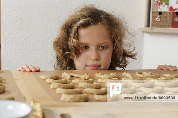 Pleased little girl looking at almond cookies