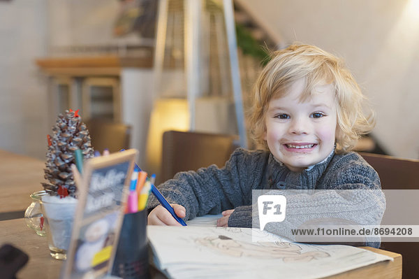 Smiling blond boy in a cafe  portrait