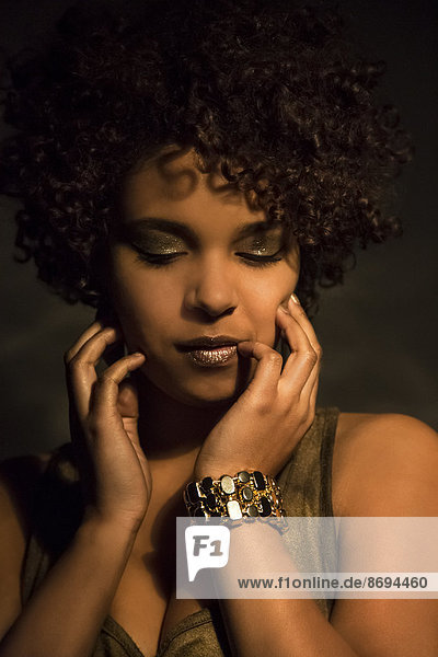 Porträt einer Afro-Amerikanerin mit goldenem Make-up und Armband