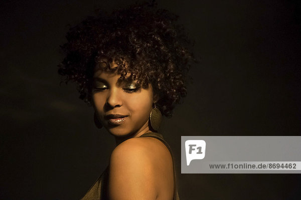Porträt einer Afroamerikanerin mit goldenem Make-up und Ohrring