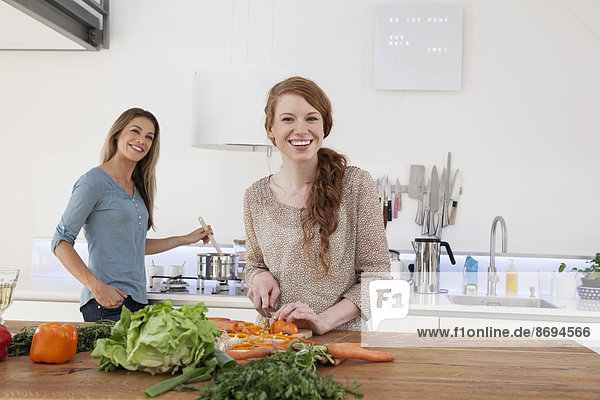 Two young female friends cooking together