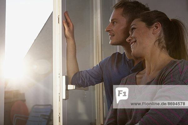 Couple standing at open window