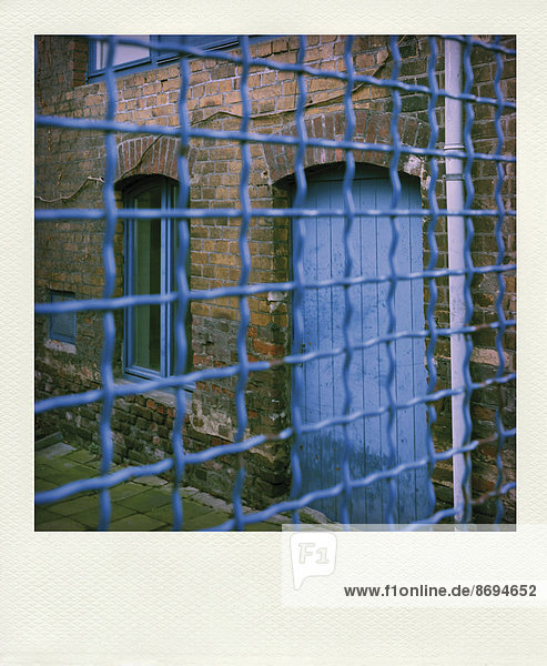 Blauer Zaun vor einem alten Haus  Teilansicht