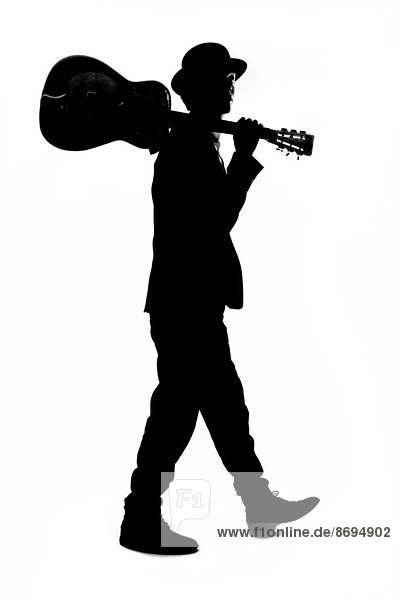 Silhouette of young man with bowler hat holding guitar on his shoulder