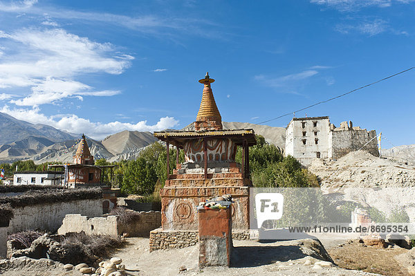 Tibetischer Buddhismus  bunt angemalter Stupa  rechts hinten alter Königspalast  weiße Ruine  Dzong  Charang  Tsarang  Oberes Mustang oder Lo  Nepal