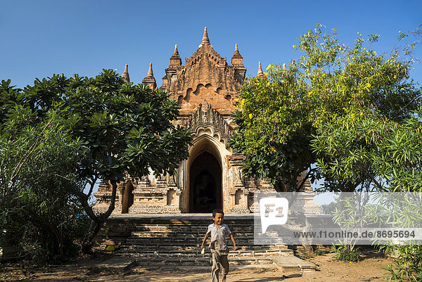 Boy in front of a temple stupa or pagoda in the temple complex of the Plateau of Bagan Mandalay Division Myanmar or Burma