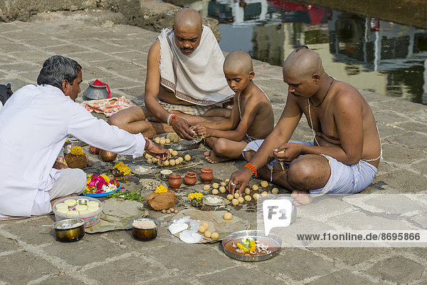 Two men, a boy and a pandit or priest are performing Dashkriya or Asthi ...