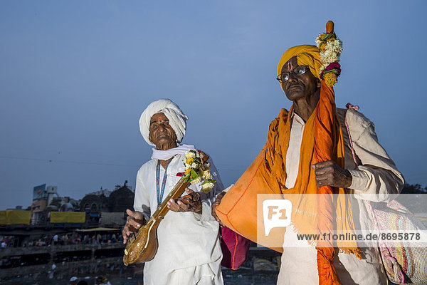 Zwei Gläubige mit ihren Musikinstrumenten am Ufer des heiligen Flusses Godwari  Nasik  Maharashtra  Indien