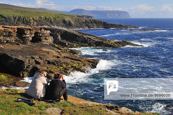 Two female tourists on the lookout with binoculars  Yesnaby  Mainland  Orkney  Scotland  United Kingdom