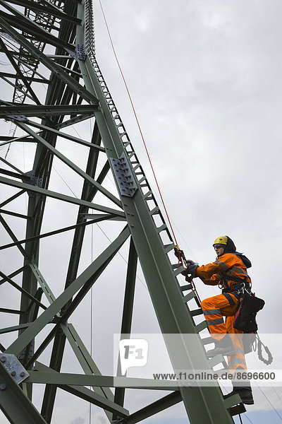 Freileitungsmonteur besteigt einen Mast um Leiterseilzugarbeiten auf einem neu errichteten Höchstspannungsmast durchzuführen  Mönchenholzhausen  Thüringen  Deutschland