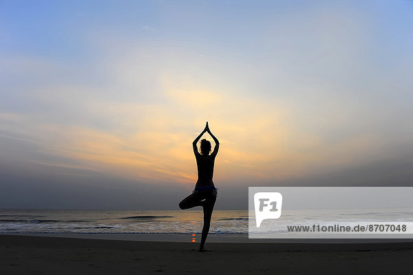 Woman doing yoga on a beach at dusk  Kerala  India
