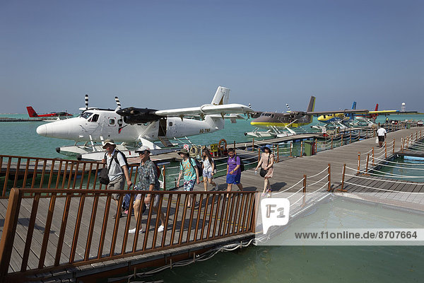 Tourists leaving the pontoon with hydroplanes moored  De Havilland Canada DHC-6 300 Twin Otter  Malé International Airport  Hulhulé  Maldives