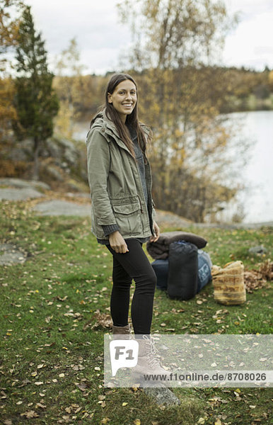 Porträt einer glücklichen Frau  die beim Camping am Seeufer steht.