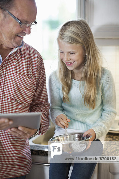 Großvater und Enkelin beim Kochen in der Küche mit dem digitalen Tablett