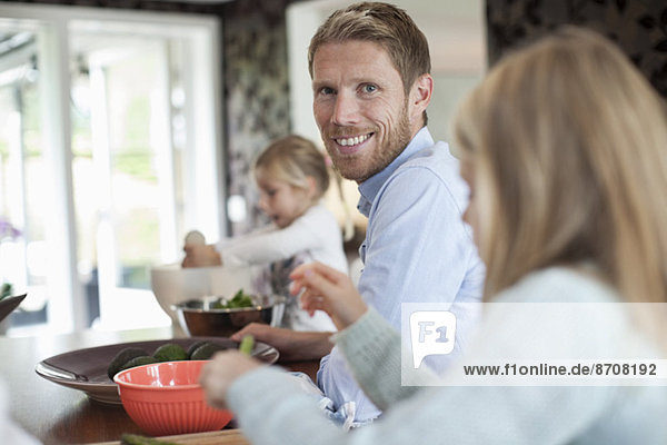 Porträt des lächelnden Mannes beim Kochen mit Töchtern in der Küche