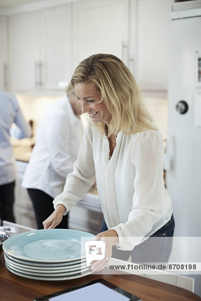 Woman arranging plates in kitchen