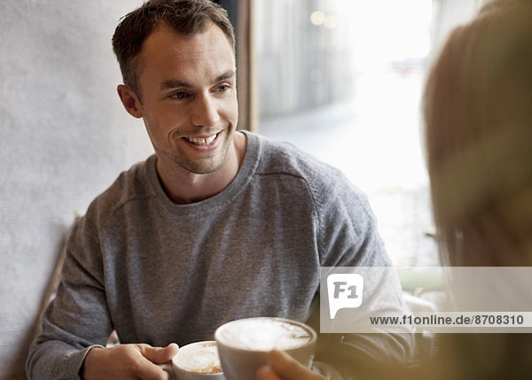 Junger Mann beim Kaffee mit Frau im Café